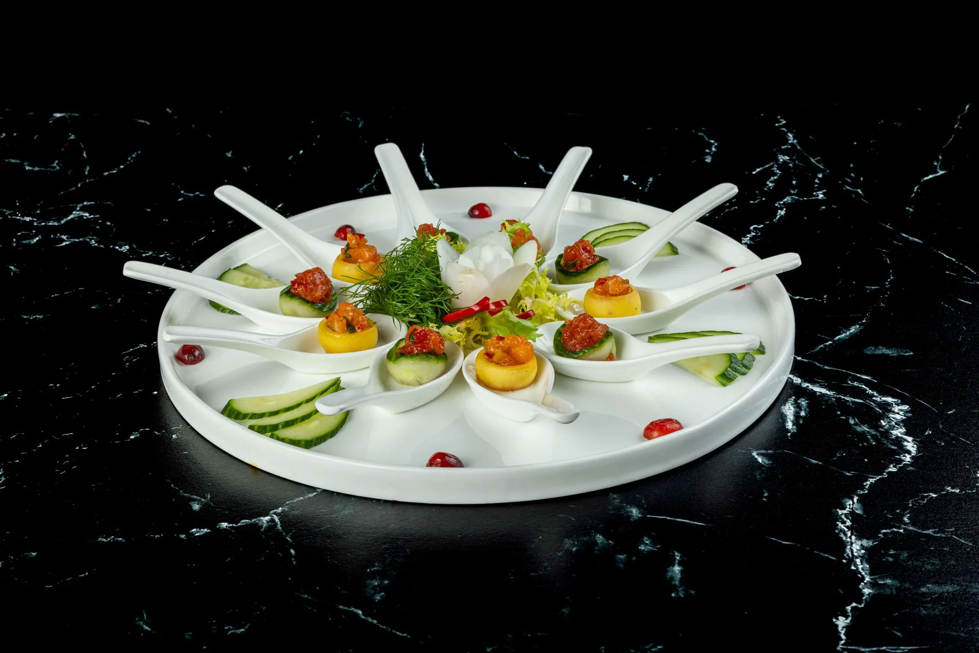 Una fuente redonda blanca de canapés en cuchara y huevos rellenos con eneldo y pimiento