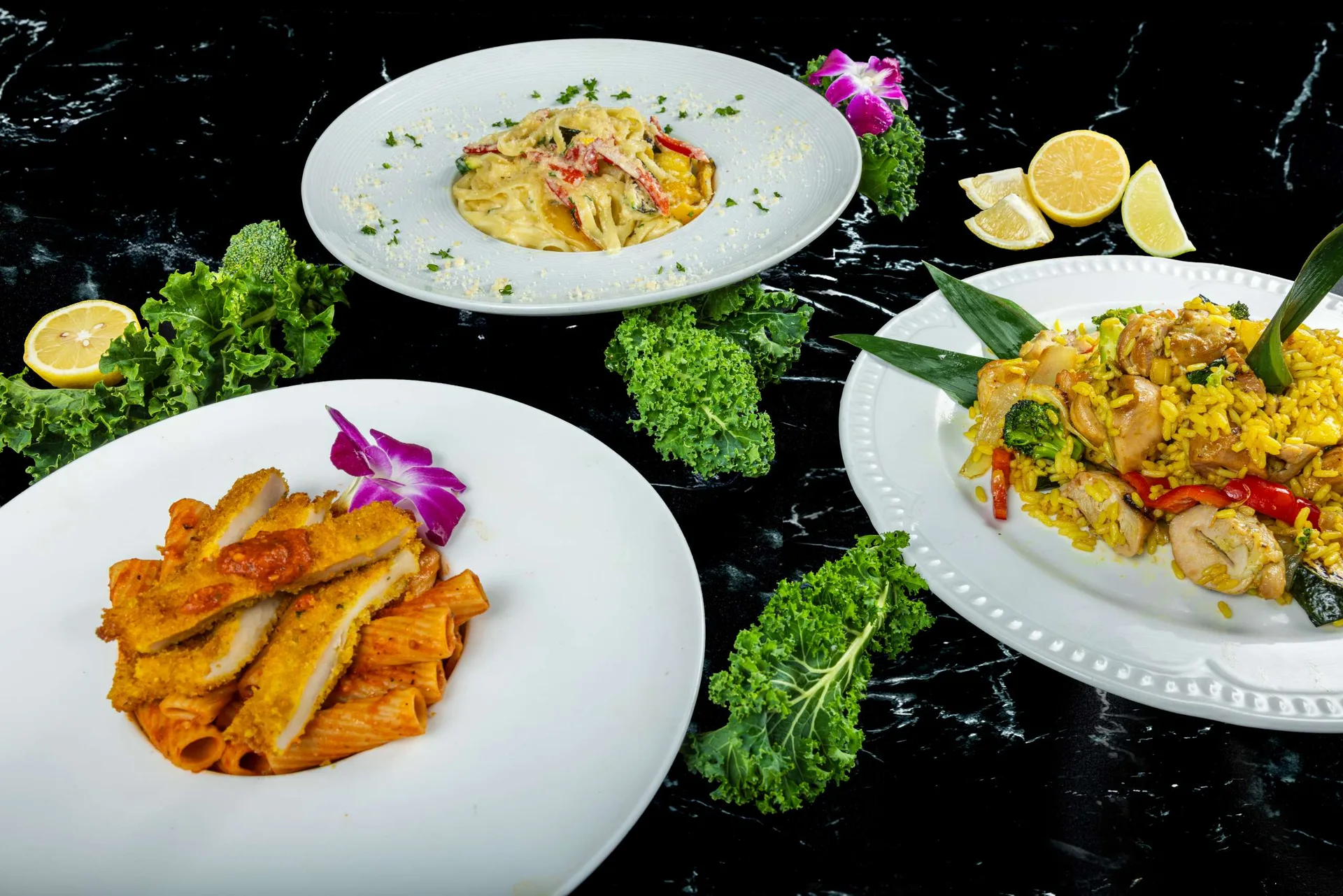 Tres platos juntos: penne en salsa de tomate, fettuccine alfredo y pollo con arroz al azafrán