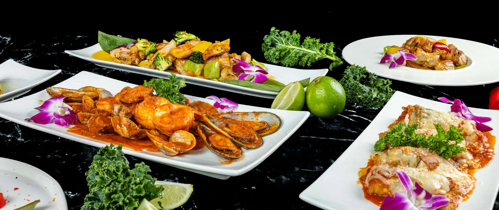 Gambas y mejillones en salsa roja en una fuente larga con lima, en una fila de platos calientes