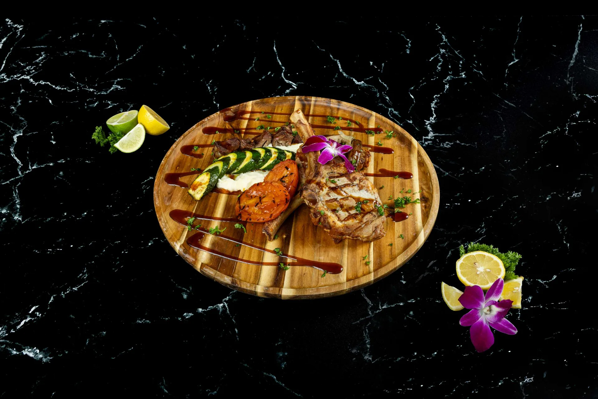 Una tabla redonda de madera con filete, salmón y calabacín a la parrilla, balsámico y orquídeas