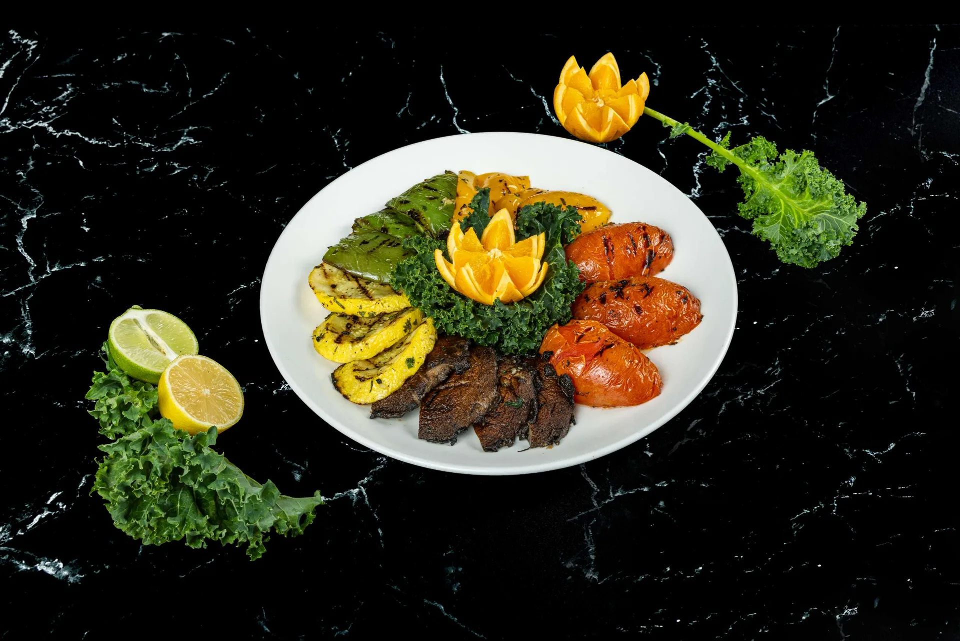 Una fuente ovalada de calabaza a la parrilla, filete en lonchas y salchichas con una flor de naranja tallada
