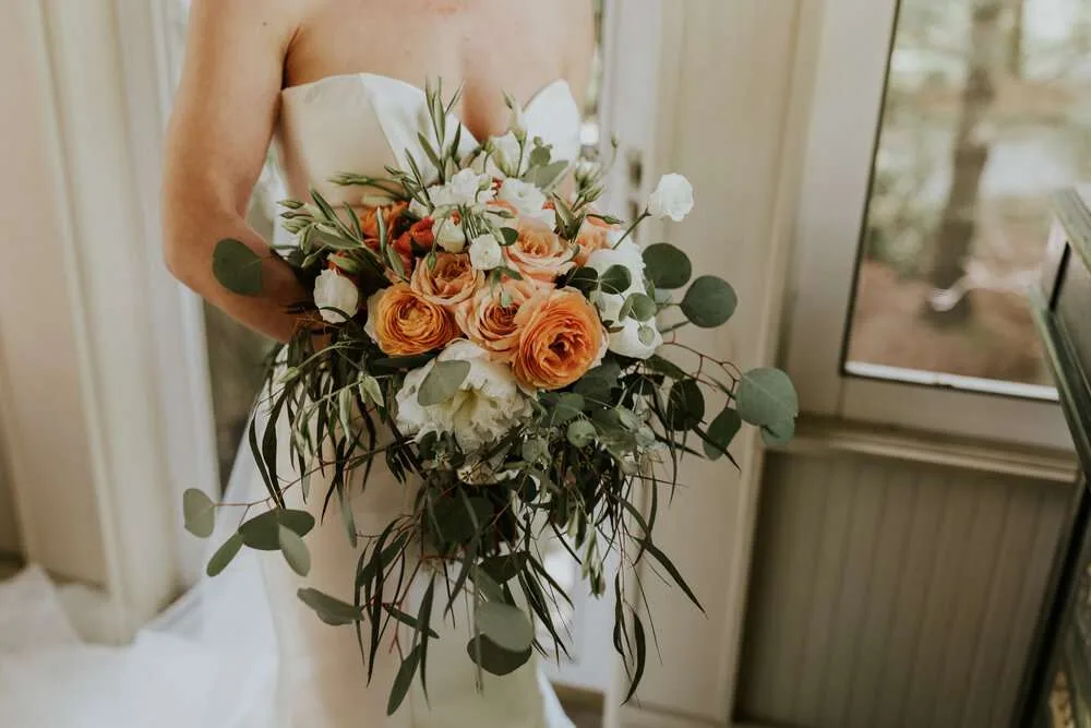 Bride with beautiful bouquet of seasonal flowers prepares for her wedding