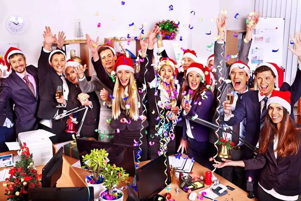 Happy group of people in Santa hats at corporate holiday party.