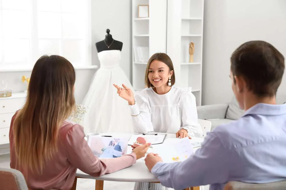 Female wedding planner discussing ceremony and wedding planning timeline with clients
