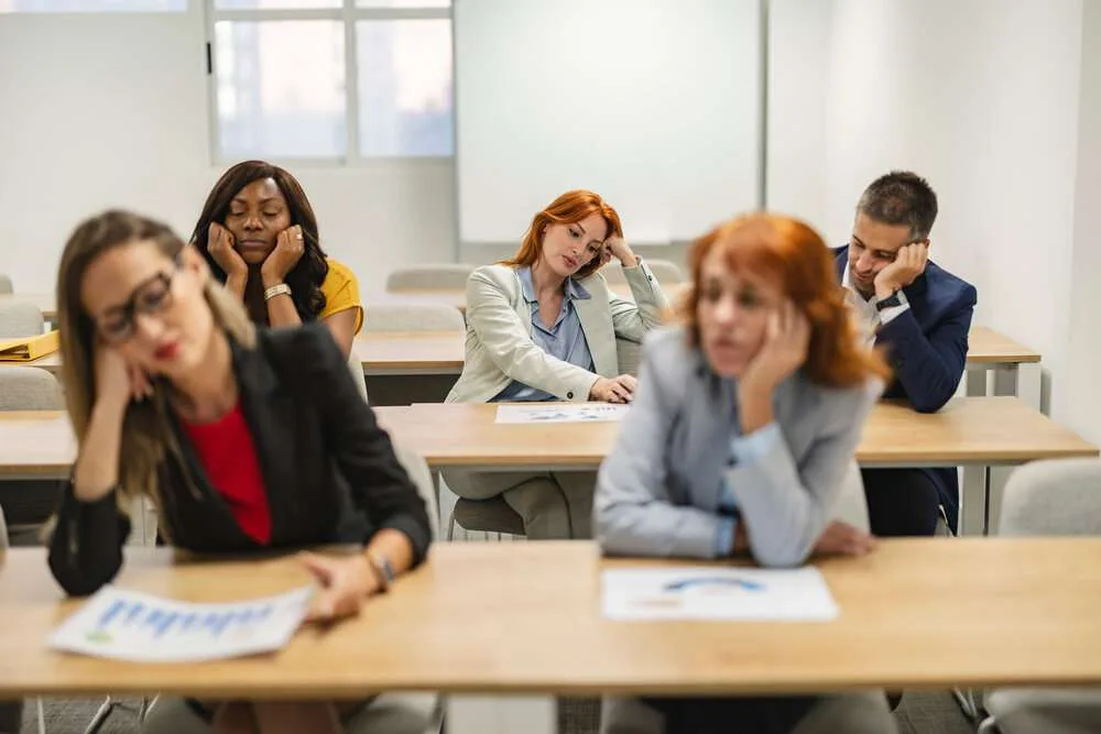 Business team showing signs of boredom and fatigue during a long corporate training event