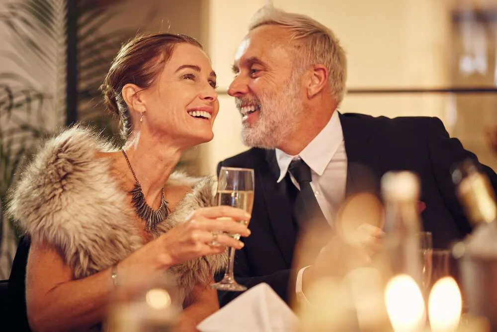 Happy, senior and couple celebration dinner with wine glass and smile of woman with funny man. Party with elegant, classy and formal style