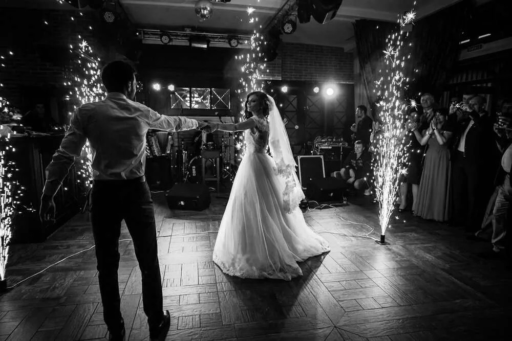 Beautiful newlywed couple first dance at wedding reception surrounded by smoke and lights and sparks